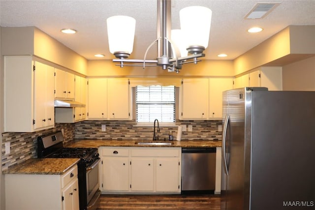 kitchen featuring stainless steel appliances, sink, decorative backsplash, and dark stone counters