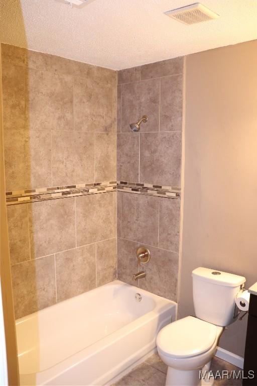 full bathroom with tile patterned floors, toilet, tiled shower / bath, a textured ceiling, and vanity