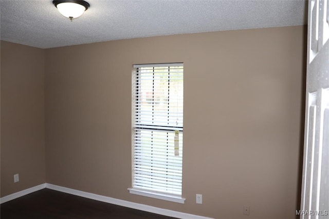 unfurnished room featuring dark hardwood / wood-style flooring and a textured ceiling