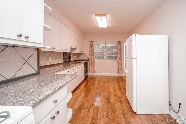 kitchen featuring backsplash, white cabinets, and white fridge