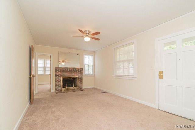 unfurnished living room featuring ceiling fan, light colored carpet, ornamental molding, and a brick fireplace