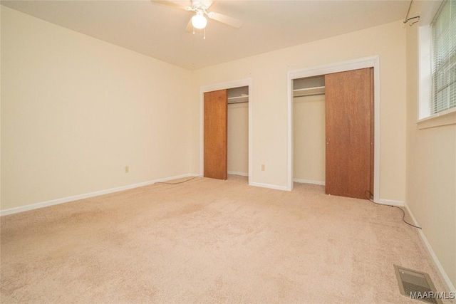 unfurnished bedroom featuring multiple closets, carpet, and ceiling fan