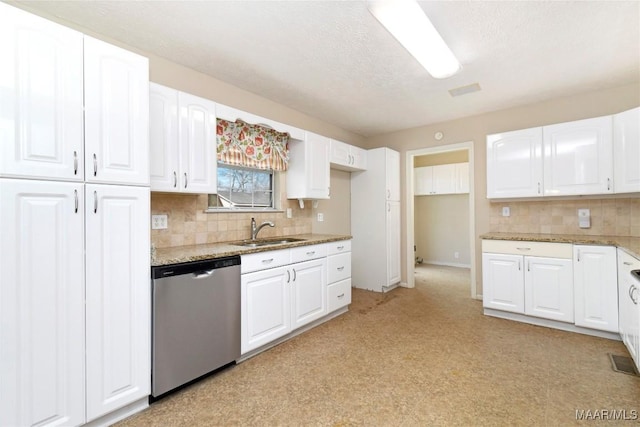 kitchen with stone counters, stainless steel dishwasher, sink, and white cabinets