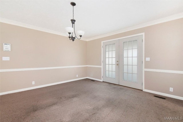 carpeted empty room featuring ornamental molding, a chandelier, and french doors