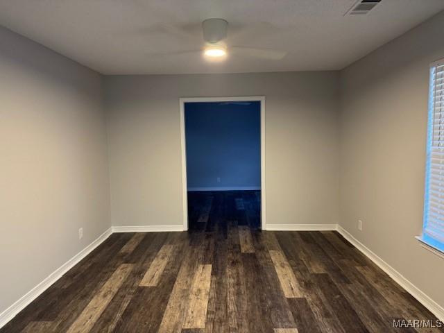 unfurnished room with dark wood-type flooring and ceiling fan