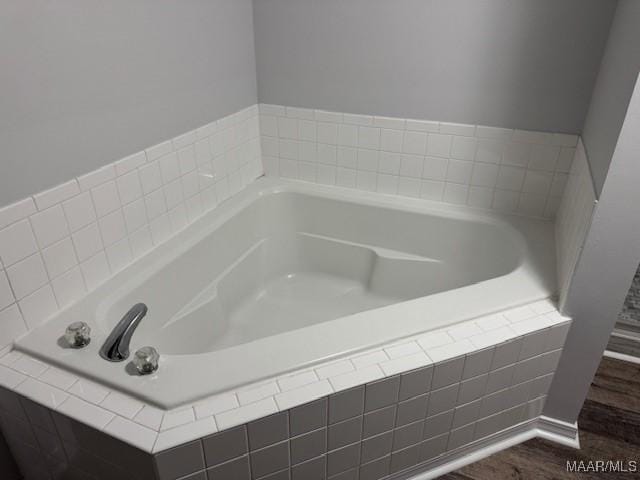 bathroom with tiled tub and hardwood / wood-style floors