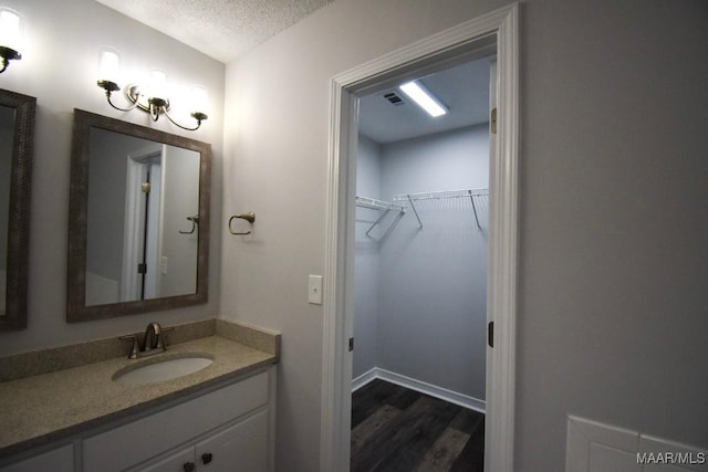 6515 Redland Rd, Wetumpka, AL 36093 - bathroom with vanity, a textured ceiling, a spacious closet, and wood finished floors