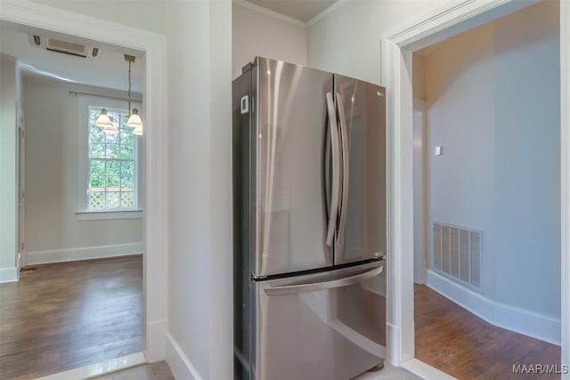 kitchen featuring pendant lighting, ornamental molding, stainless steel fridge, and dark hardwood / wood-style flooring