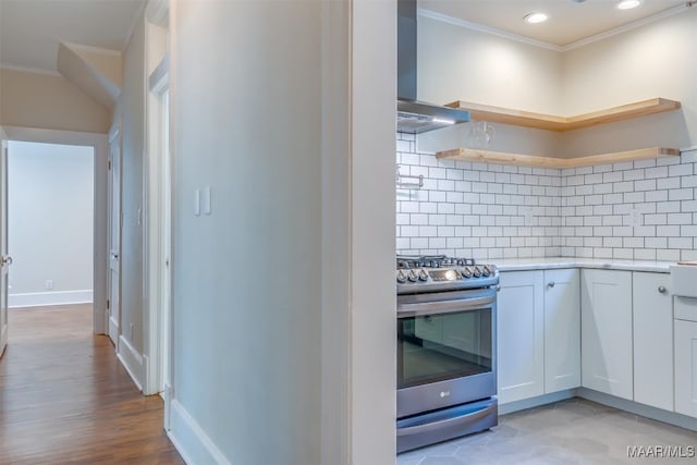 kitchen with white cabinetry, crown molding, stainless steel stove, decorative backsplash, and wall chimney range hood