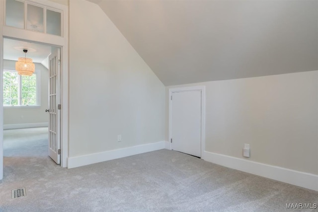 additional living space with vaulted ceiling and light carpet