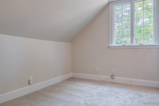 bonus room with vaulted ceiling and light colored carpet