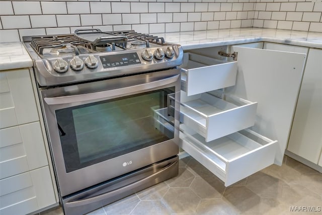 details with white cabinetry, stainless steel range with gas stovetop, and decorative backsplash