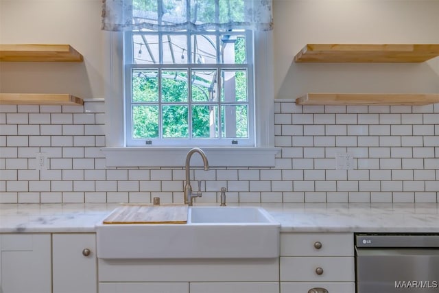 kitchen featuring white cabinetry, sink, dishwashing machine, backsplash, and light stone countertops