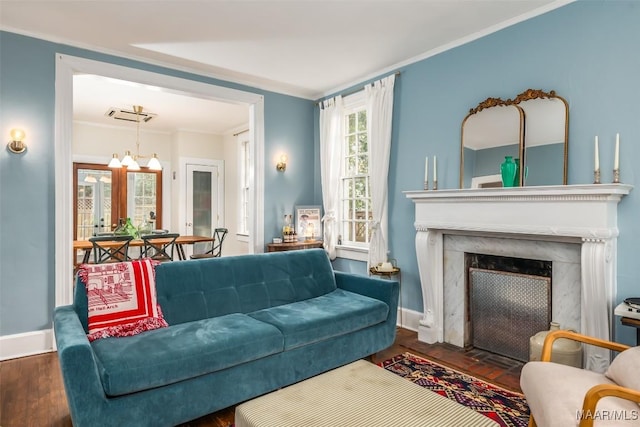 living room featuring dark hardwood / wood-style flooring, crown molding, a high end fireplace, and a chandelier