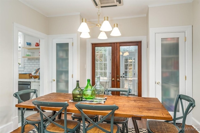 dining space with french doors, ornamental molding, a chandelier, and hardwood / wood-style flooring