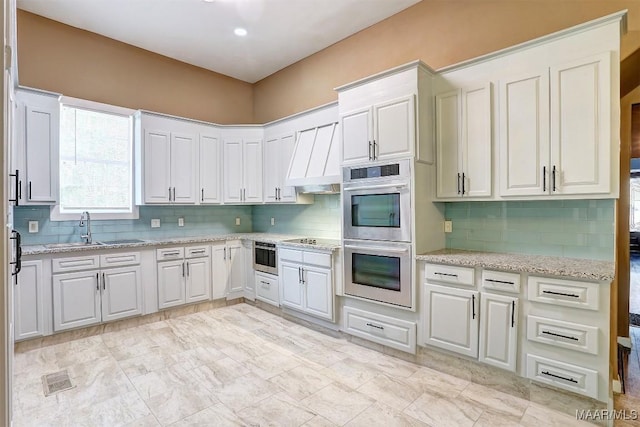 kitchen featuring light stone countertops, stainless steel double oven, white cabinets, and black electric cooktop