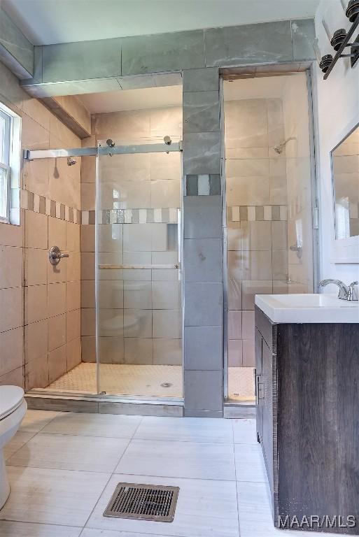 bathroom with walk in shower, vanity, toilet, and tile patterned flooring