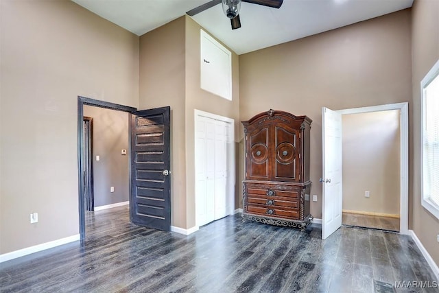 foyer with dark wood-type flooring, ceiling fan, and a towering ceiling