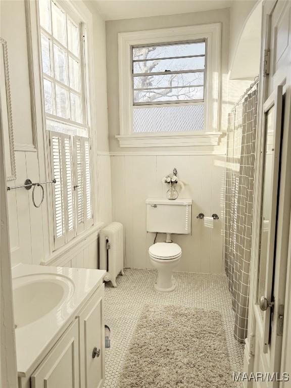 bathroom featuring radiator heating unit, tile patterned flooring, vanity, walk in shower, and toilet