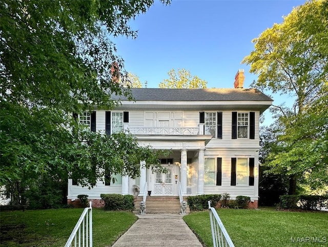 colonial house featuring a balcony, covered porch, and a front lawn