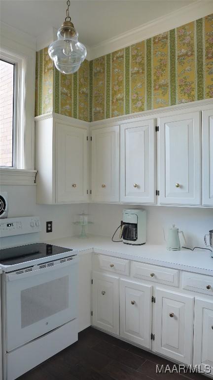 kitchen featuring pendant lighting, white cabinetry, dark hardwood / wood-style flooring, white range with electric cooktop, and crown molding