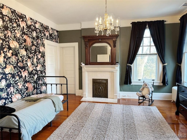 bedroom featuring a brick fireplace, a chandelier, and dark hardwood / wood-style flooring