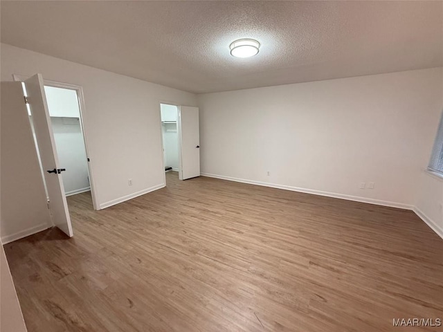 unfurnished room with light hardwood / wood-style flooring and a textured ceiling