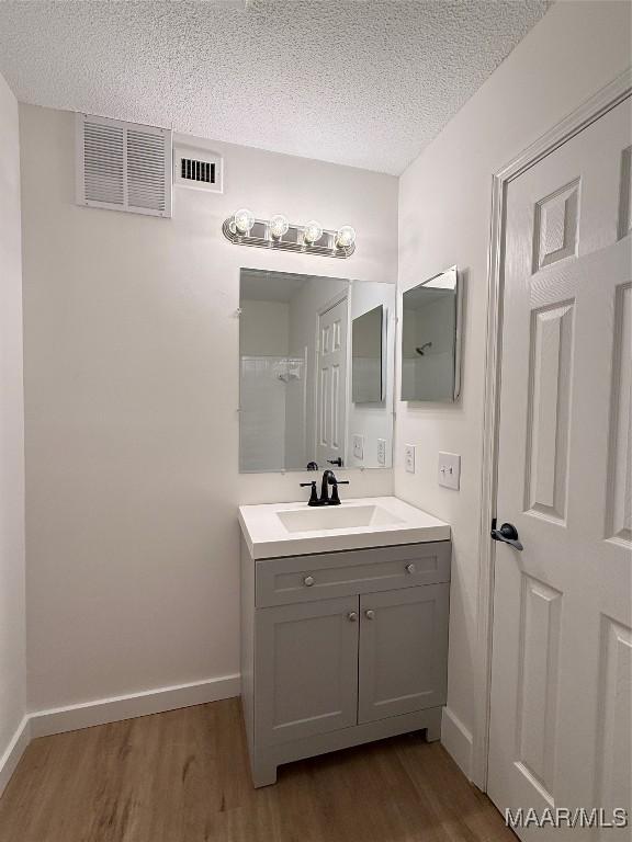 bathroom featuring wood-type flooring, vanity, and a textured ceiling