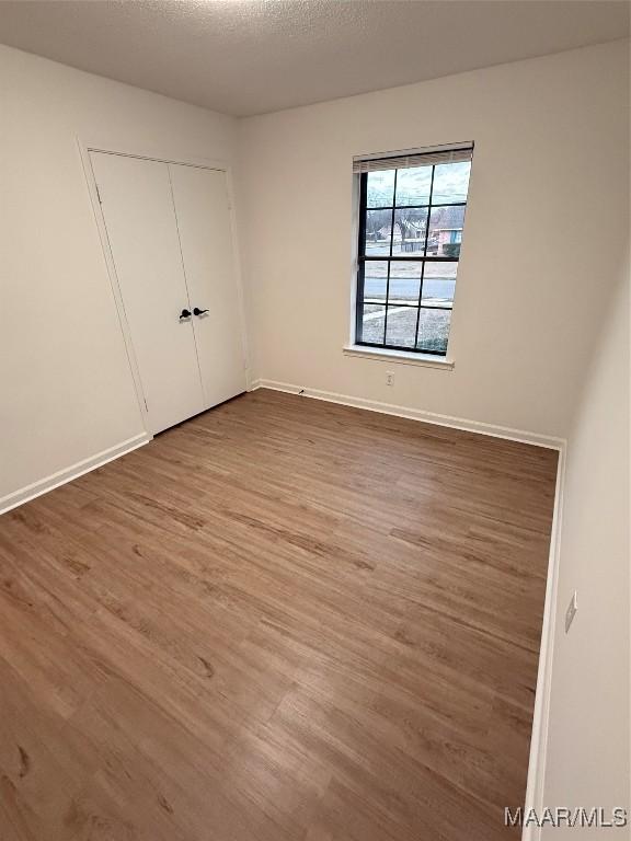 unfurnished bedroom with hardwood / wood-style flooring, a textured ceiling, and a closet