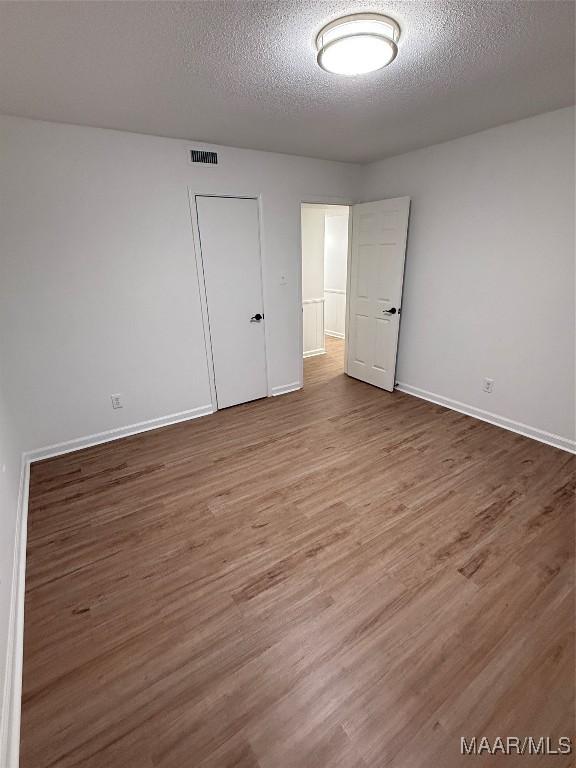 unfurnished room with hardwood / wood-style floors and a textured ceiling