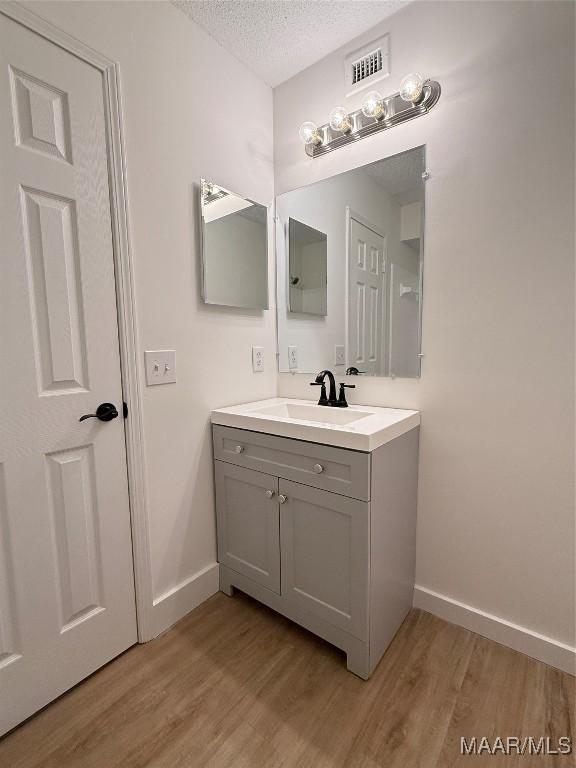 bathroom featuring hardwood / wood-style flooring, vanity, and a textured ceiling