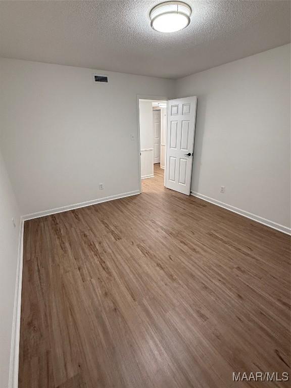 unfurnished room with a textured ceiling and dark hardwood / wood-style flooring