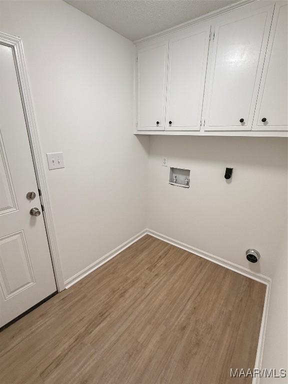 clothes washing area featuring cabinets, wood-type flooring, hookup for a washing machine, and a textured ceiling