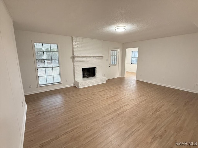 unfurnished living room with hardwood / wood-style flooring, a fireplace, and a textured ceiling