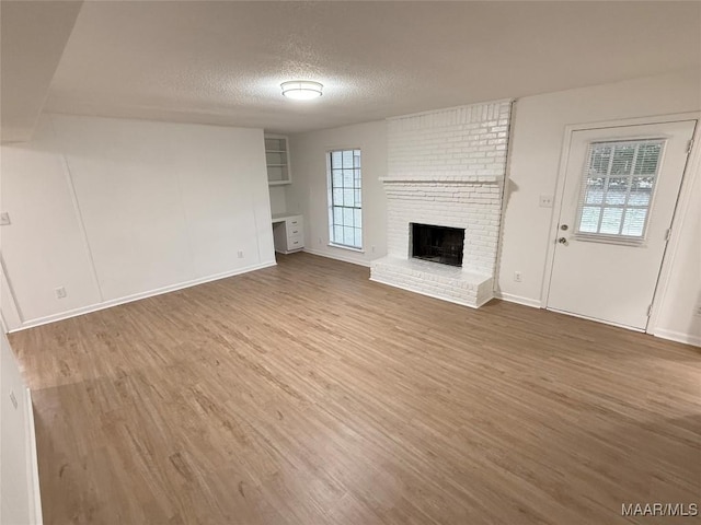 unfurnished living room featuring hardwood / wood-style flooring, a healthy amount of sunlight, a fireplace, and a textured ceiling