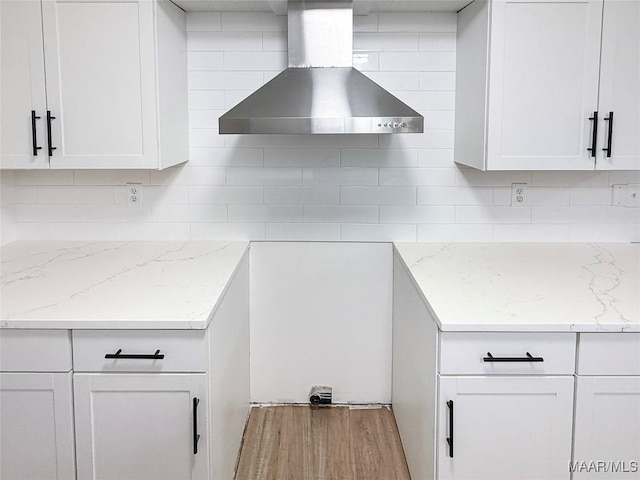 kitchen featuring white cabinetry, wall chimney range hood, and tasteful backsplash