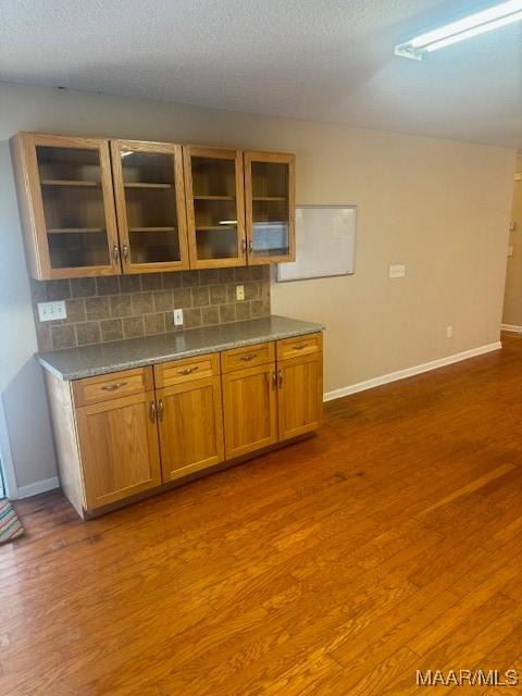 kitchen with dark wood-type flooring, backsplash, and a textured ceiling