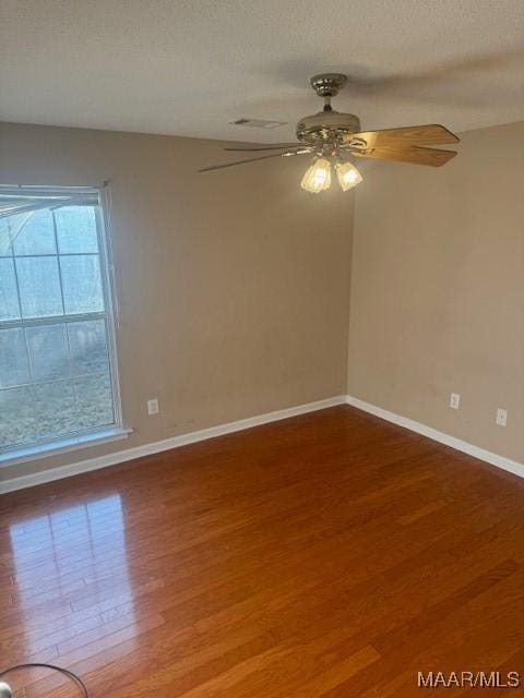 unfurnished room featuring ceiling fan, a textured ceiling, baseboards, and wood finished floors