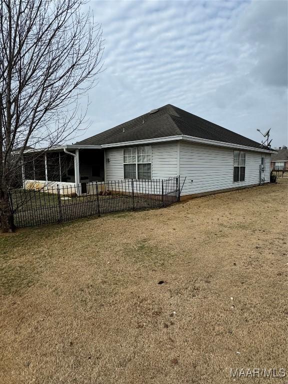 rear view of property featuring a yard and fence