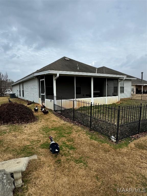 exterior space featuring a sunroom, a yard, and fence