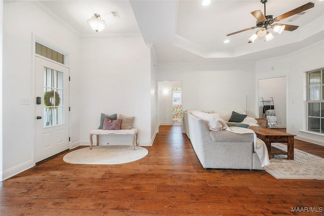 living room featuring ornamental molding, dark hardwood / wood-style flooring, and a tray ceiling