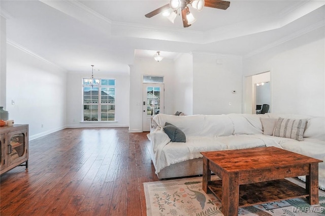 living room with dark hardwood / wood-style floors, ornamental molding, a tray ceiling, and ceiling fan with notable chandelier