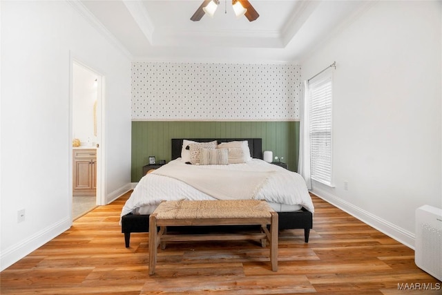 bedroom featuring crown molding, radiator heating unit, a tray ceiling, and light hardwood / wood-style flooring