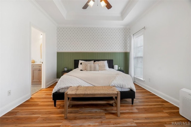 bedroom with crown molding, hardwood / wood-style flooring, radiator heating unit, connected bathroom, and a tray ceiling