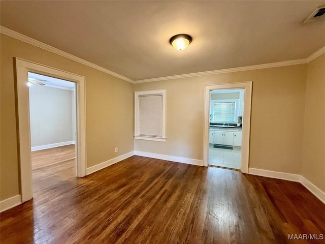 empty room with crown molding, dark hardwood / wood-style floors, and sink