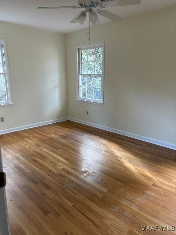 spare room with ceiling fan, a healthy amount of sunlight, and dark hardwood / wood-style flooring