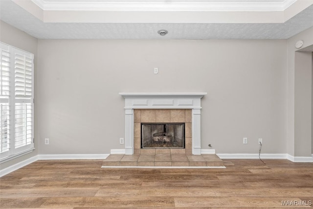 unfurnished living room with a tile fireplace, hardwood / wood-style floors, and crown molding