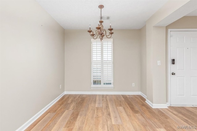 unfurnished dining area with a notable chandelier and light wood-type flooring