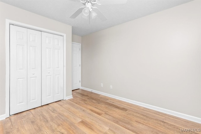 unfurnished bedroom featuring ceiling fan, a closet, a textured ceiling, and light wood-type flooring