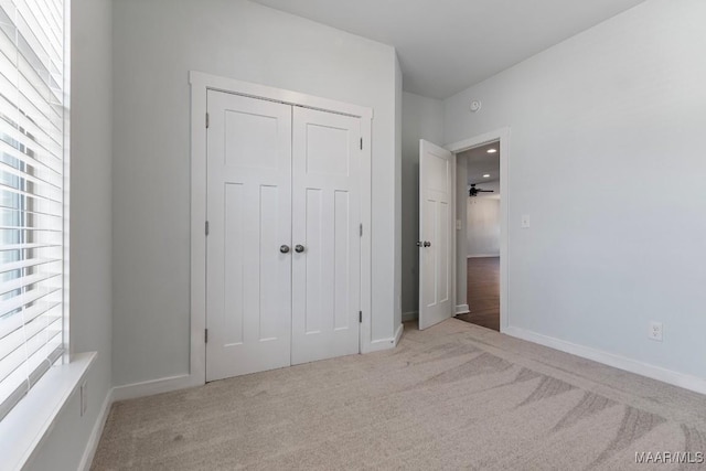 unfurnished bedroom featuring light carpet and a closet